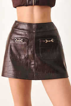 A dark brown faux-crocodile leather mini skort with two front flap pockets featuring horsebit hardware, shown on a model | FREEMARKET