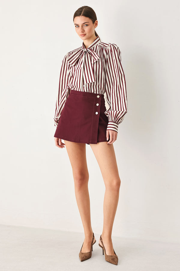 Woman wearing a dark burgundy mini skort with front buttons | FREEMARKET