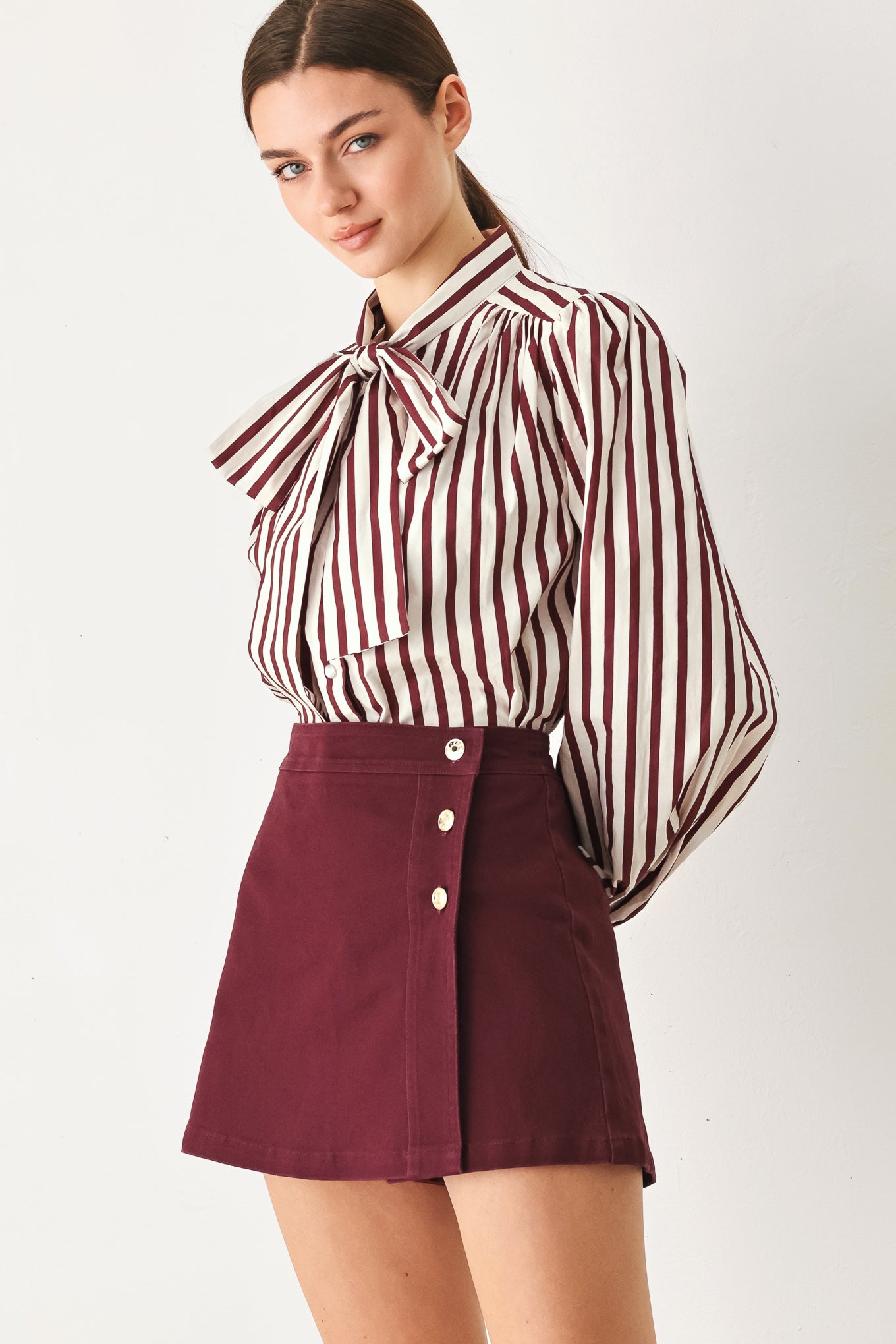 Woman wearing a dark burgundy mini skort with front buttons | FREEMARKET