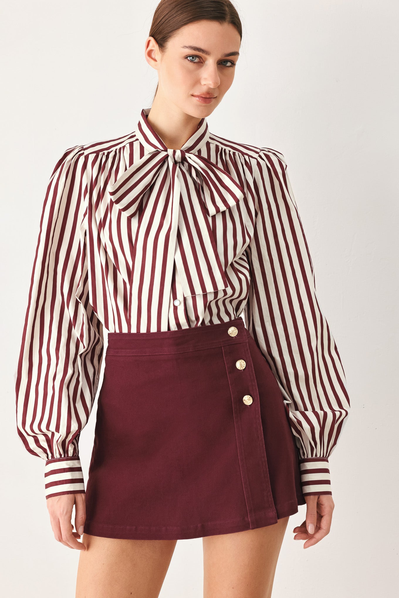 Woman wearing a dark burgundy mini skort with front buttons | FREEMARKET