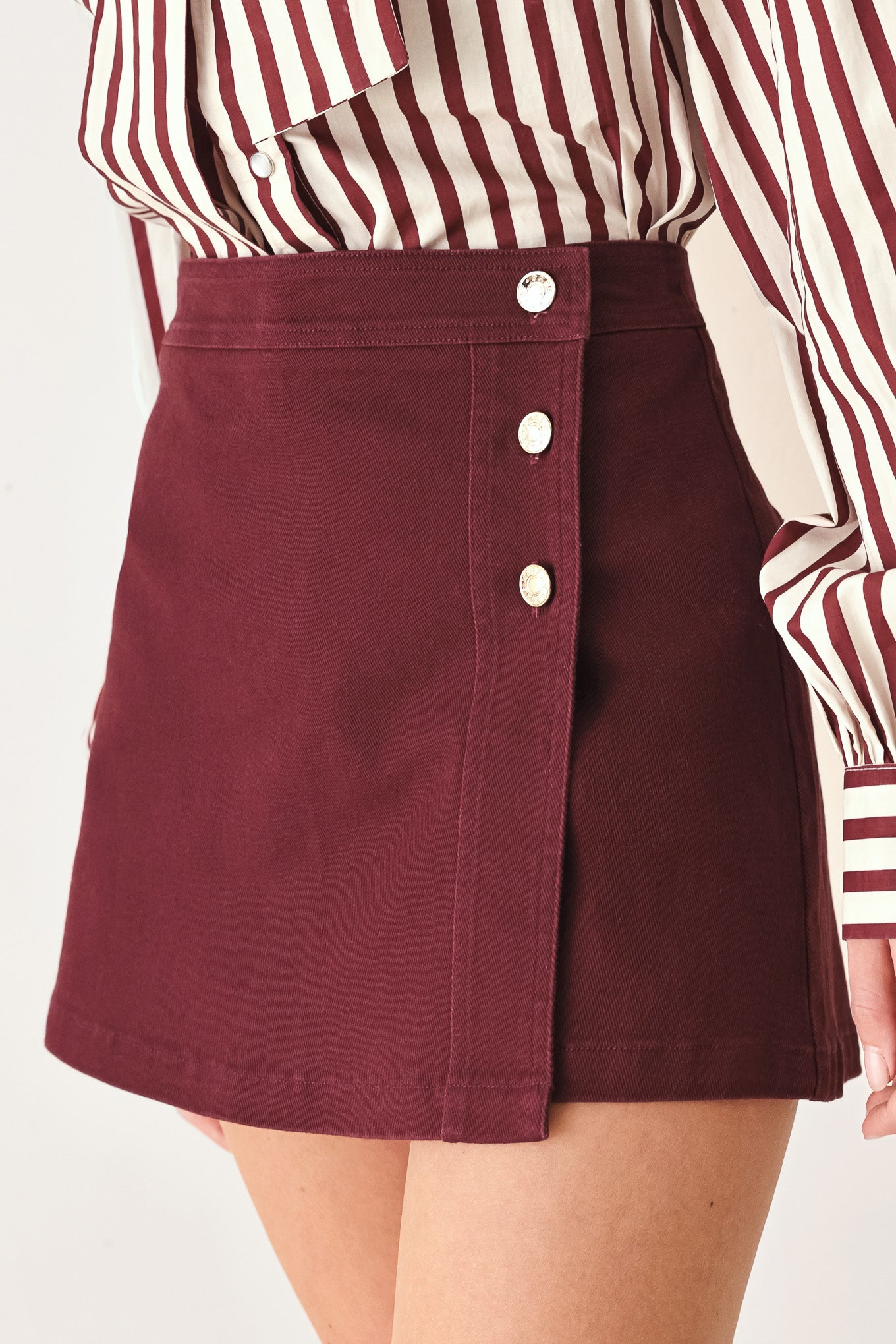Woman wearing a dark burgundy mini skort with front buttons | FREEMARKET