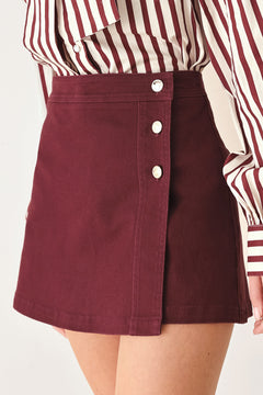 Woman wearing a dark burgundy mini skort with front buttons | FREEMARKET
