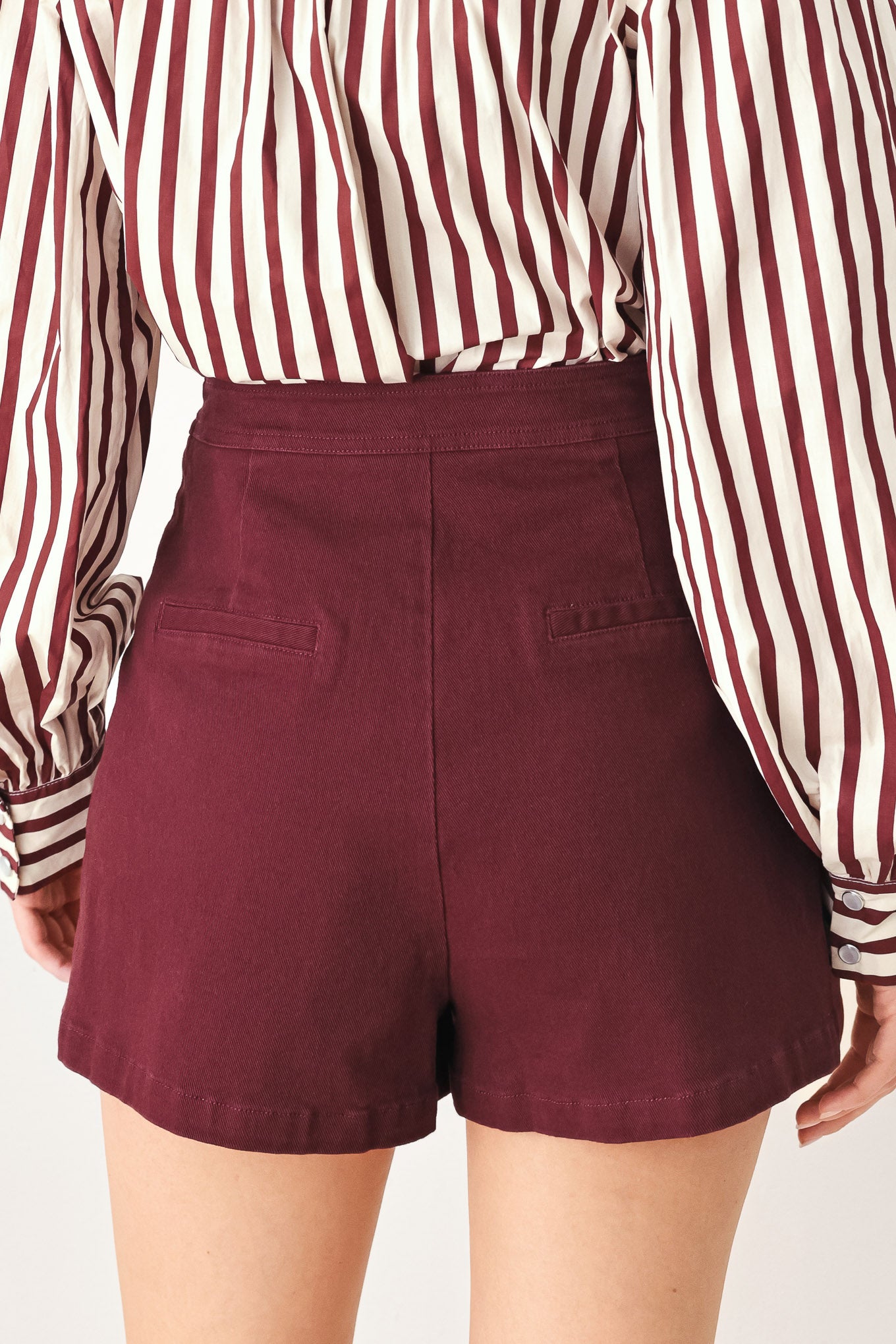 Woman wearing a dark burgundy mini skort with front buttons | FREEMARKET