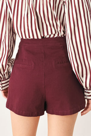 Woman wearing a dark burgundy mini skort with front buttons | FREEMARKET