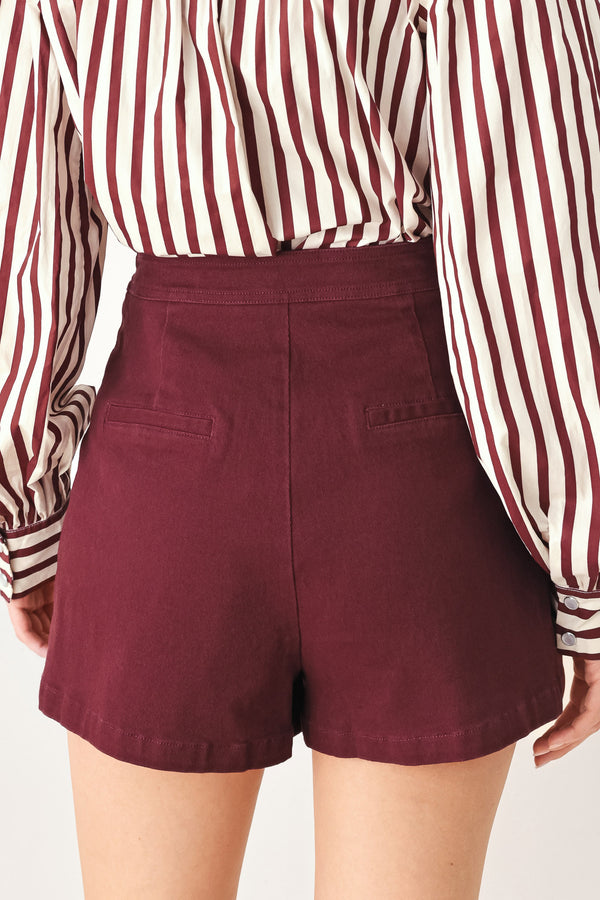 Woman wearing a dark burgundy mini skort with front buttons | FREEMARKET