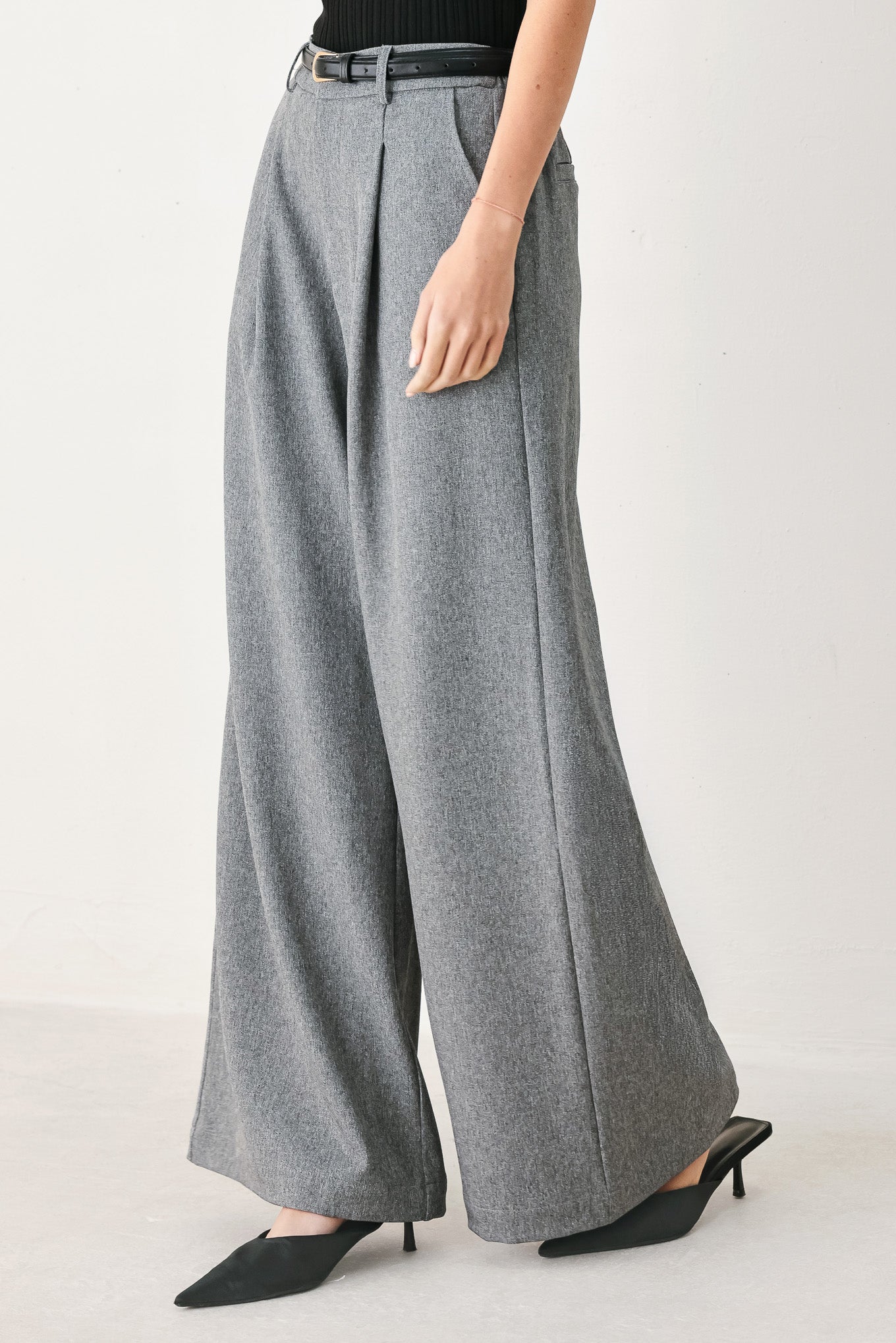 Woman wearing gray wide-leg pant with front closure, single pleat, pockets, and black belt | FREEMARKET