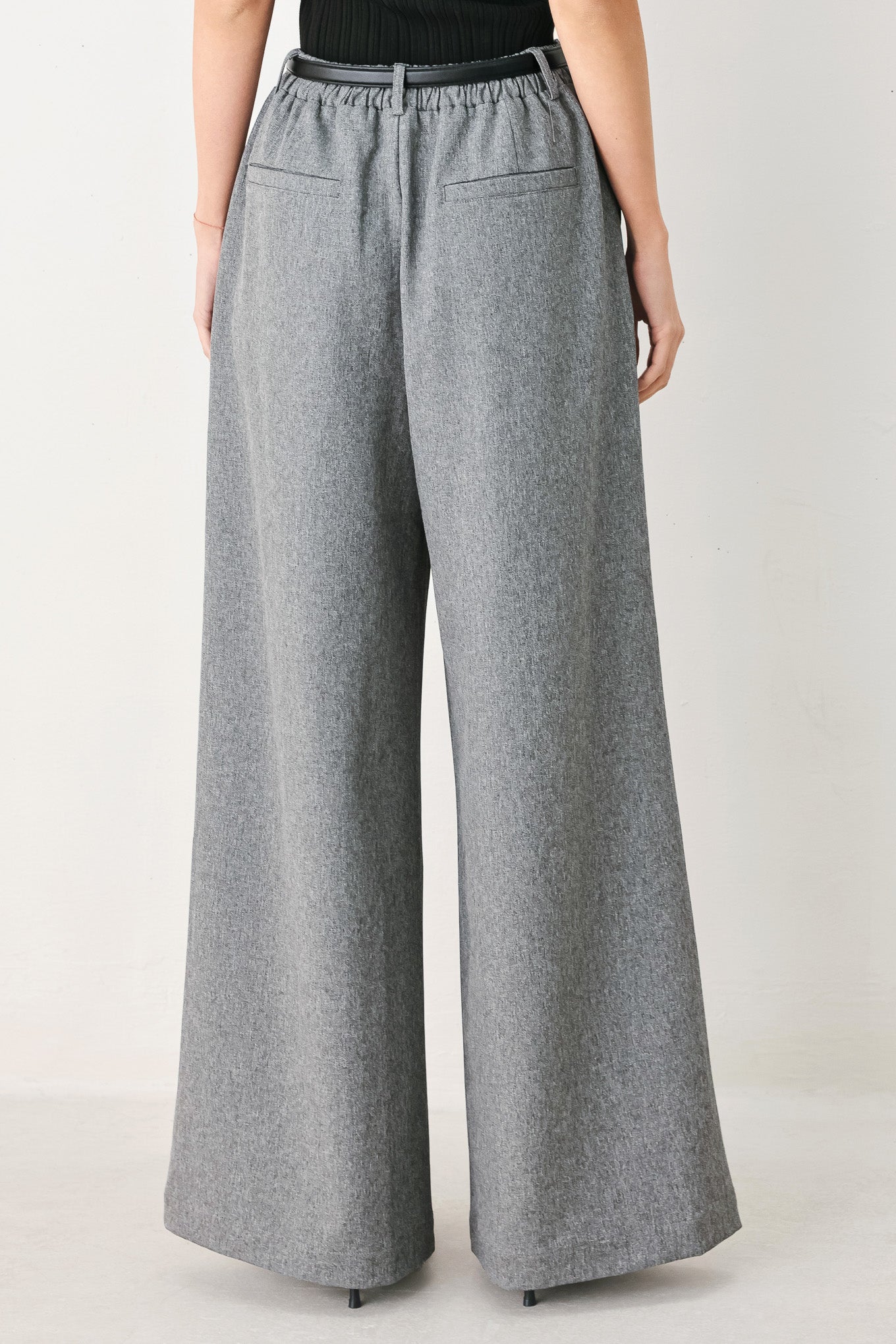 Woman wearing gray wide-leg pant with front closure, single pleat, pockets, and black belt | FREEMARKET