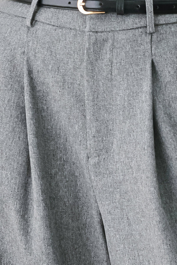 Woman wearing gray wide-leg pant with front closure, single pleat, pockets, and black belt | FREEMARKET