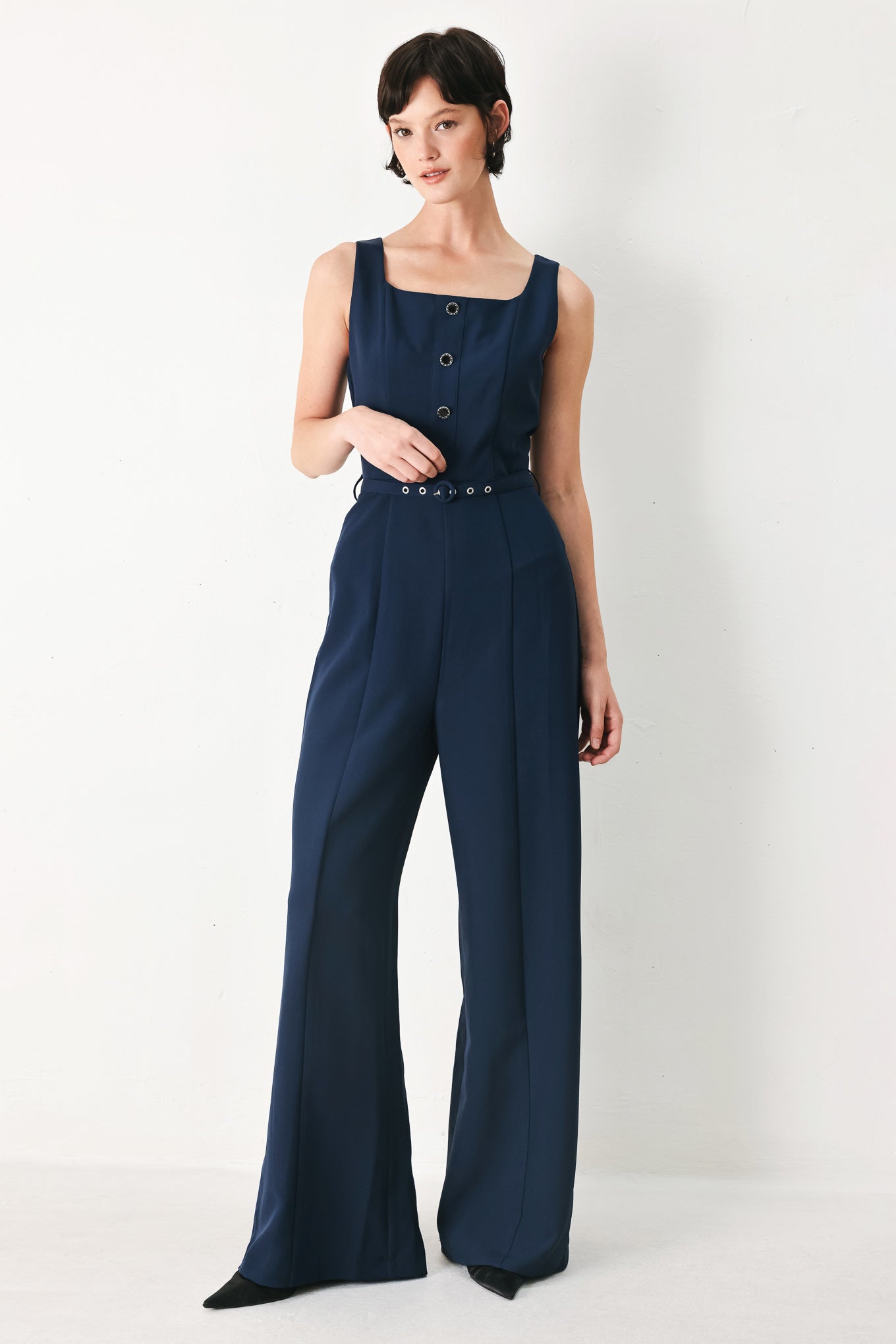 Woman wearing a sleeveless navy blue jumpsuit featuring square neckline, front button detail, self belt, wide leg and back zipper closure | FREEMARKET