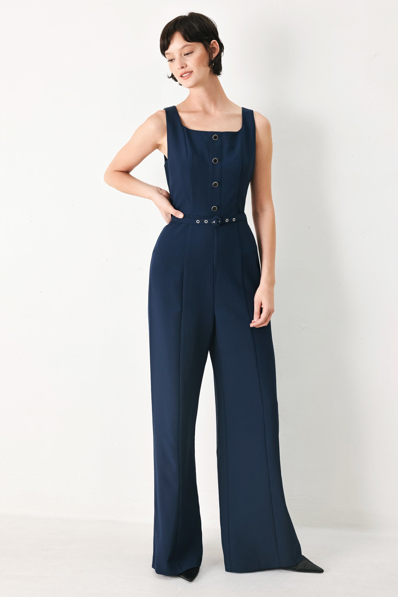 Woman wearing a sleeveless navy blue jumpsuit featuring square neckline, front button detail, self belt, wide leg and back zipper closure | FREEMARKET
