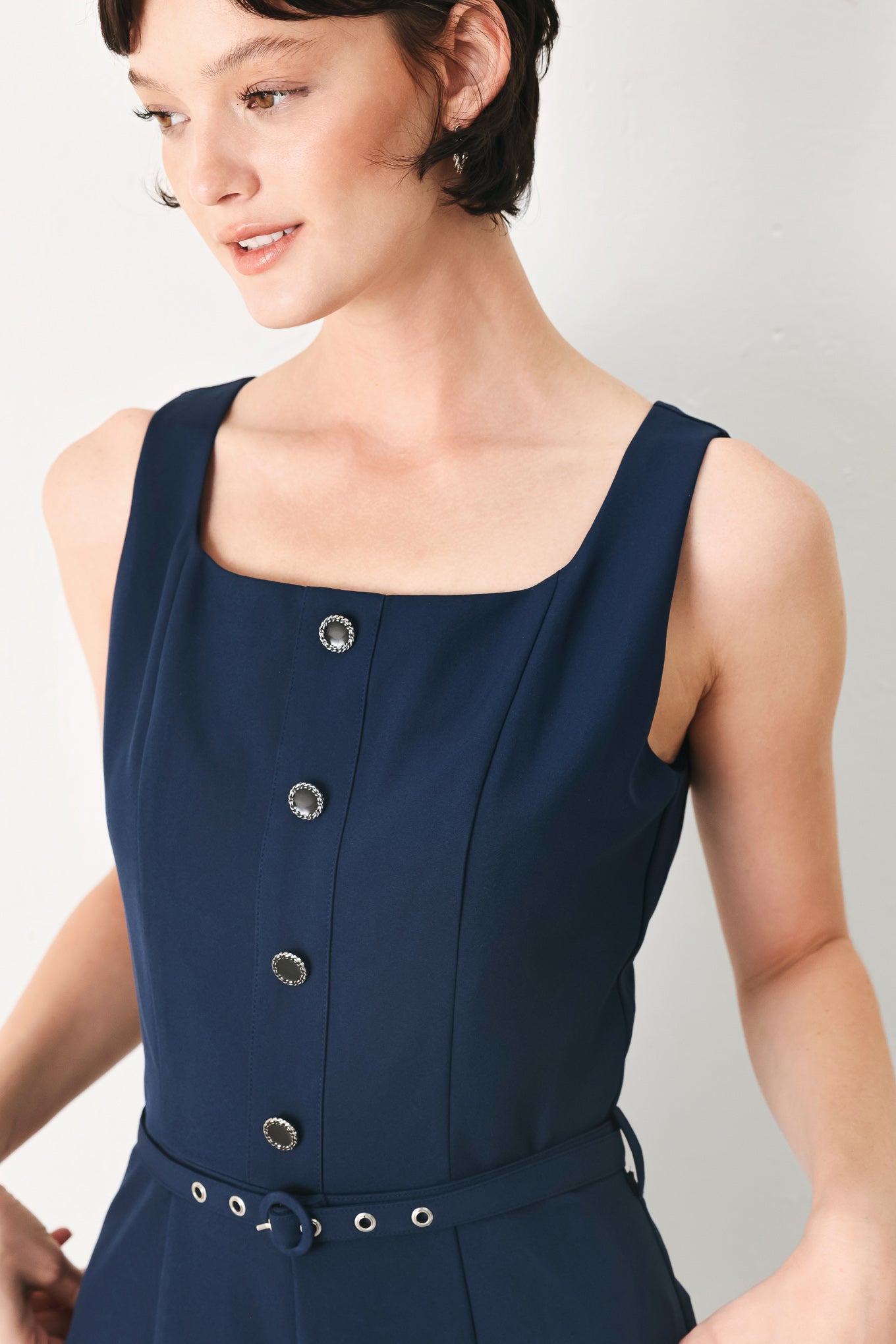 Woman wearing a sleeveless navy blue jumpsuit featuring square neckline, front button detail, self belt, wide leg and back zipper closure | FREEMARKET