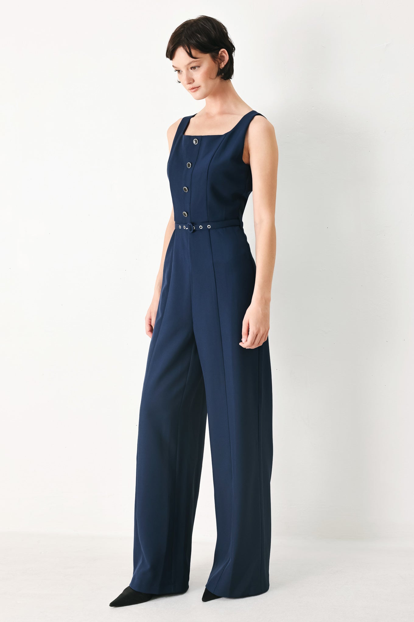 Woman wearing a sleeveless navy blue jumpsuit featuring square neckline, front button detail, self belt, wide leg and back zipper closure | FREEMARKET
