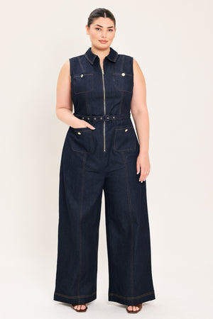 Woman wearing a dark blue denim sleeveless, wide-leg jumpsuit featuring collar, front zipper closure, and pockets | Plus Curve  FREEMARKET