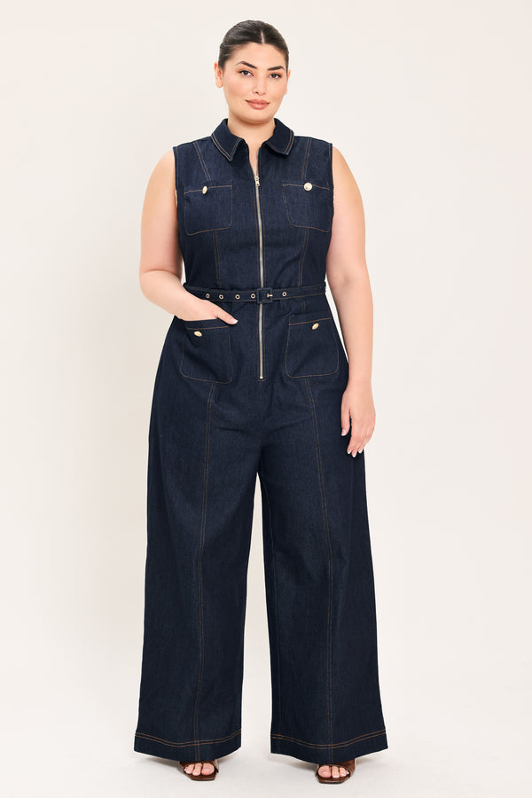 Woman wearing a dark blue denim sleeveless, wide-leg jumpsuit featuring collar, front zipper closure, and pockets | Plus Curve  FREEMARKET