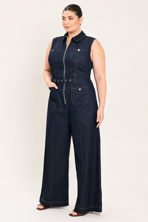 Woman wearing a dark blue denim sleeveless, wide-leg jumpsuit featuring collar, front zipper closure, and pockets | Plus Curve  FREEMARKET