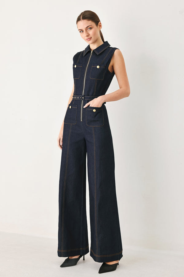 Woman wearing a dark blue denim sleeveless, wide-leg jumpsuit featuring collar, front zipper closure, and pockets | FREEMARKET