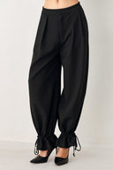 Woman wearing black harem pants with drawstring ankles and front pleats | FREEMARKET
