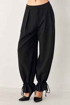 Woman wearing black harem pants with drawstring ankles and front pleats | FREEMARKET