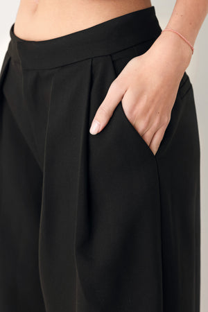 Woman wearing black harem pants with drawstring ankles and front pleats | FREEMARKET