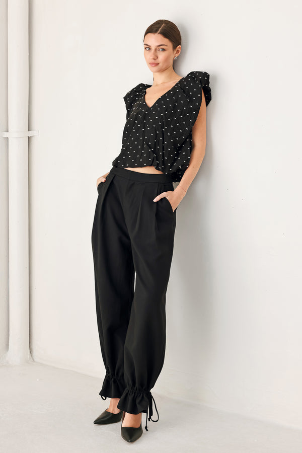Woman wearing black harem pants with drawstring ankles and front pleats | FREEMARKET