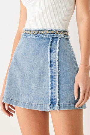 Woman wearing a light denim skort with fray edge, chain waist detail and back zipper closure | FREEMARKET