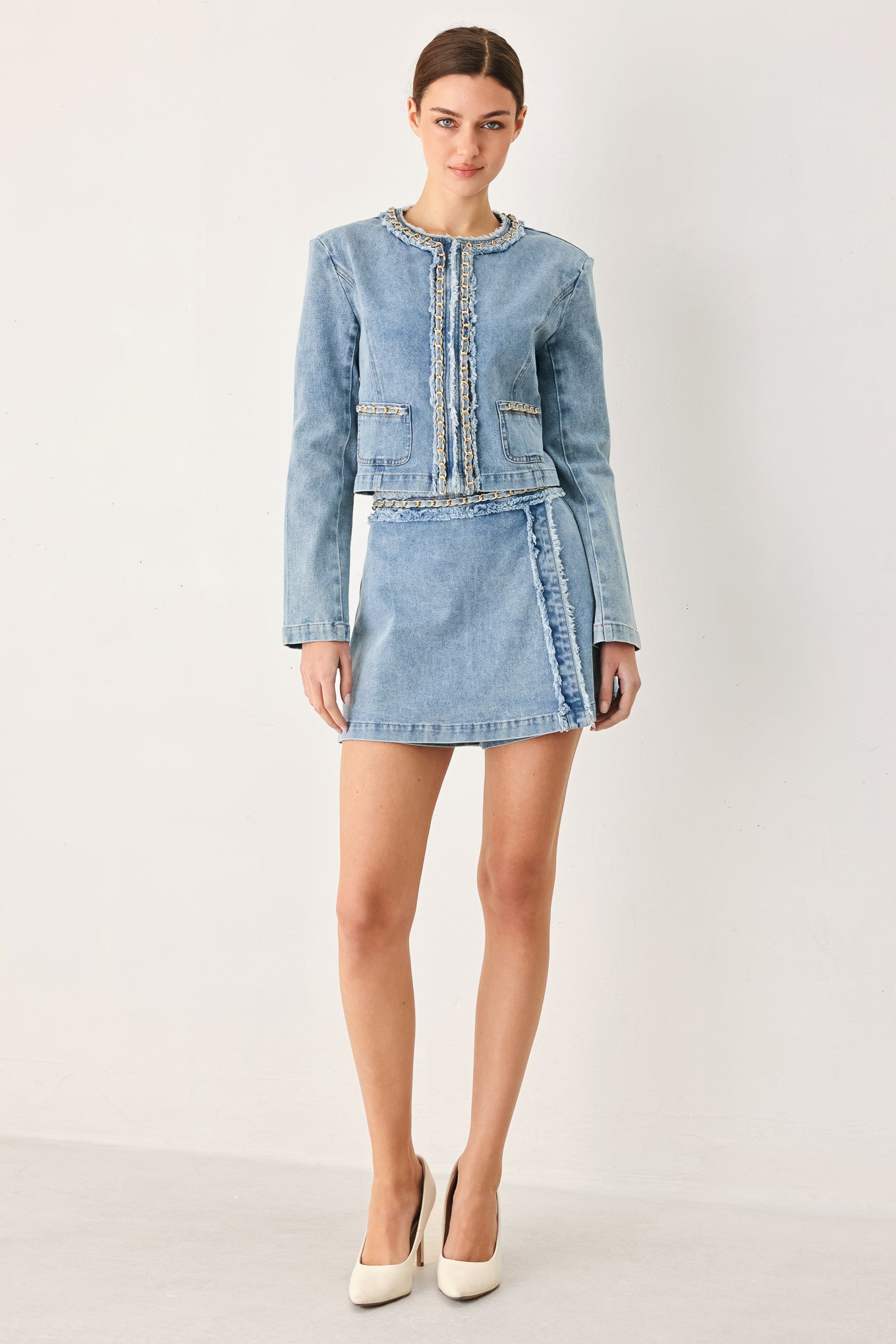 Woman wearing a light denim skort and matching jacket with fray edge, chain waist detail and back zipper closure | FREEMARKET