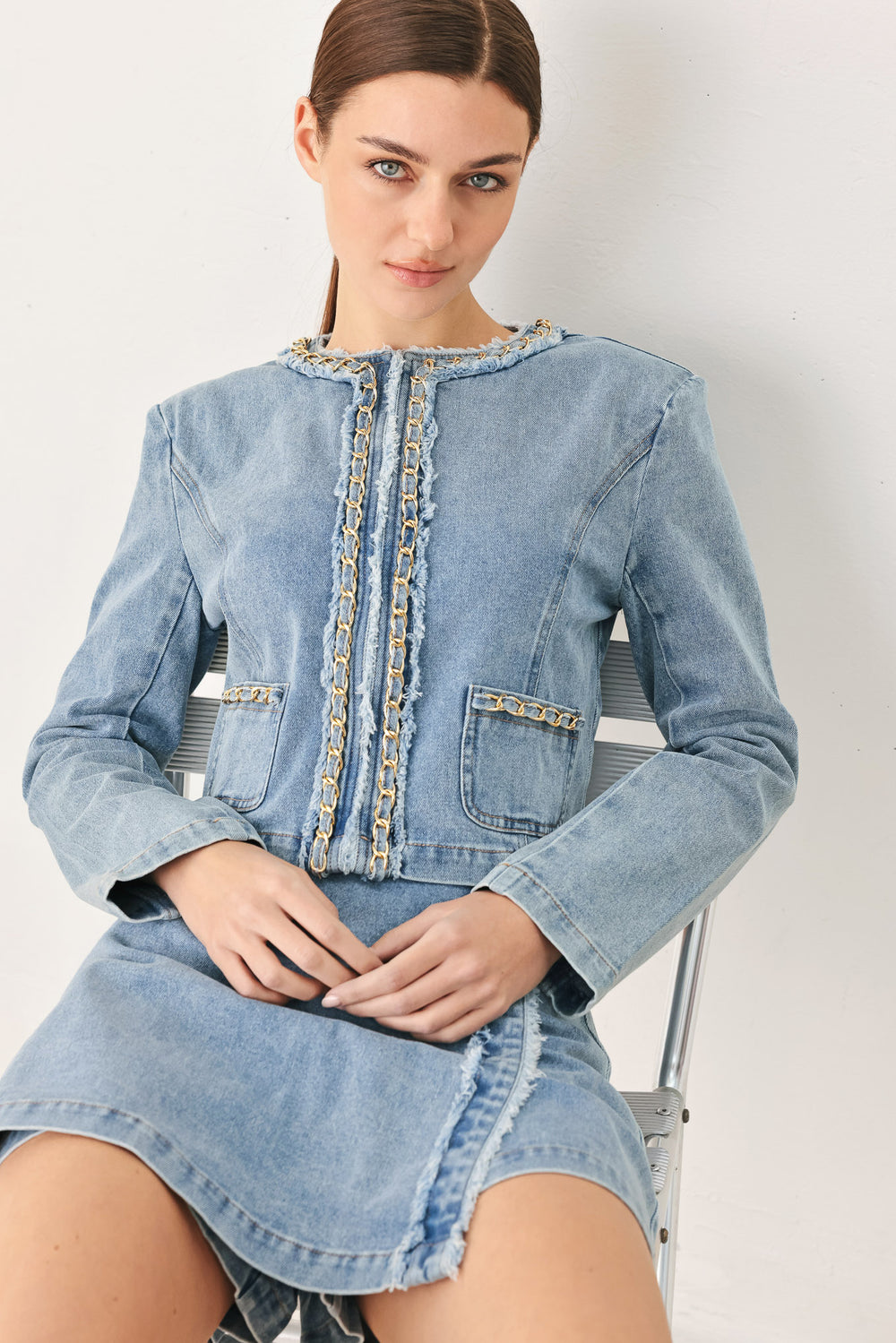 Woman wearing a light denim skort and matching jacket with fray edge, chain waist detail and back zipper closure | FREEMARKET