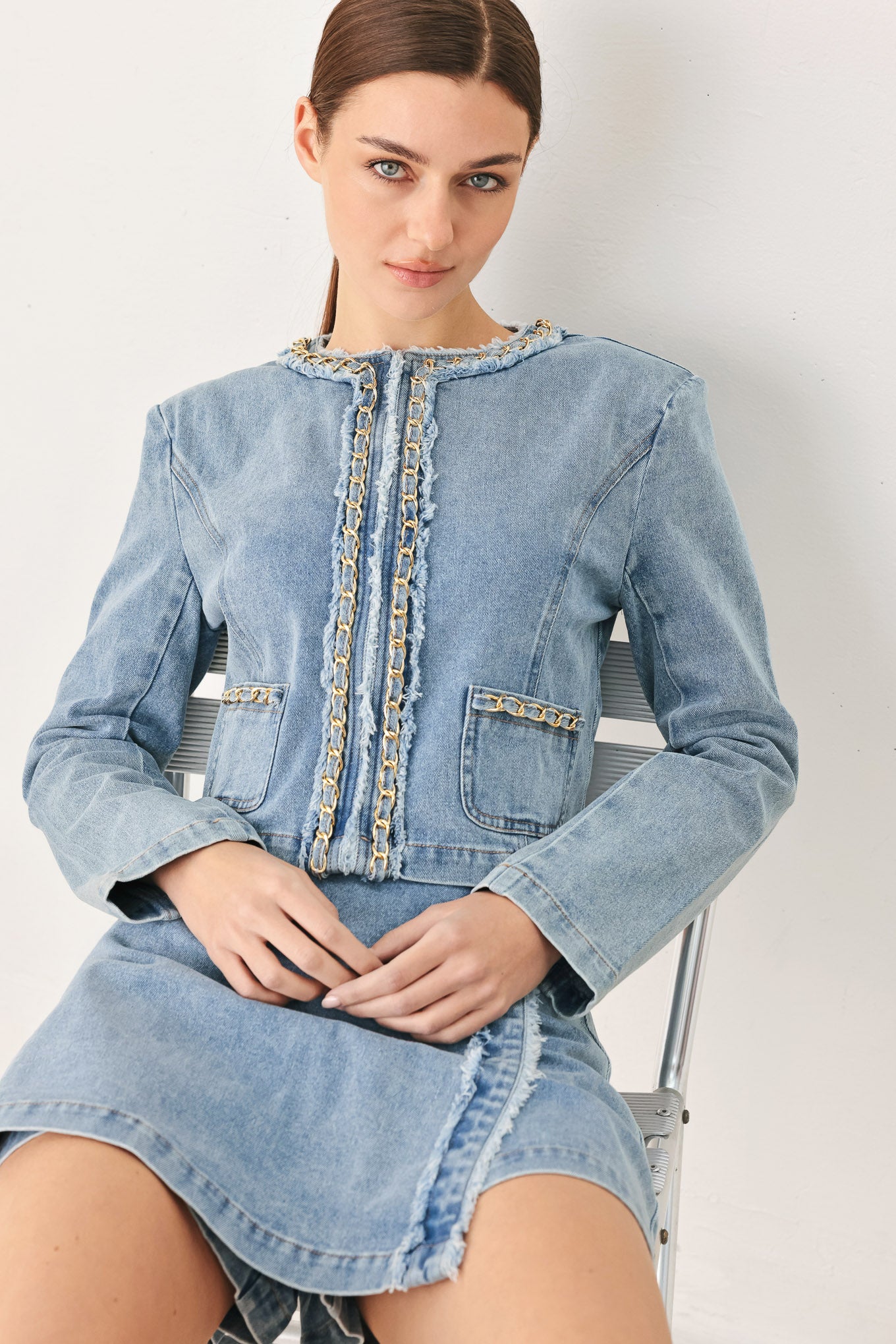 Woman wearing a light denim skort and matching jacket with fray edge, chain waist detail and back zipper closure | FREEMARKET