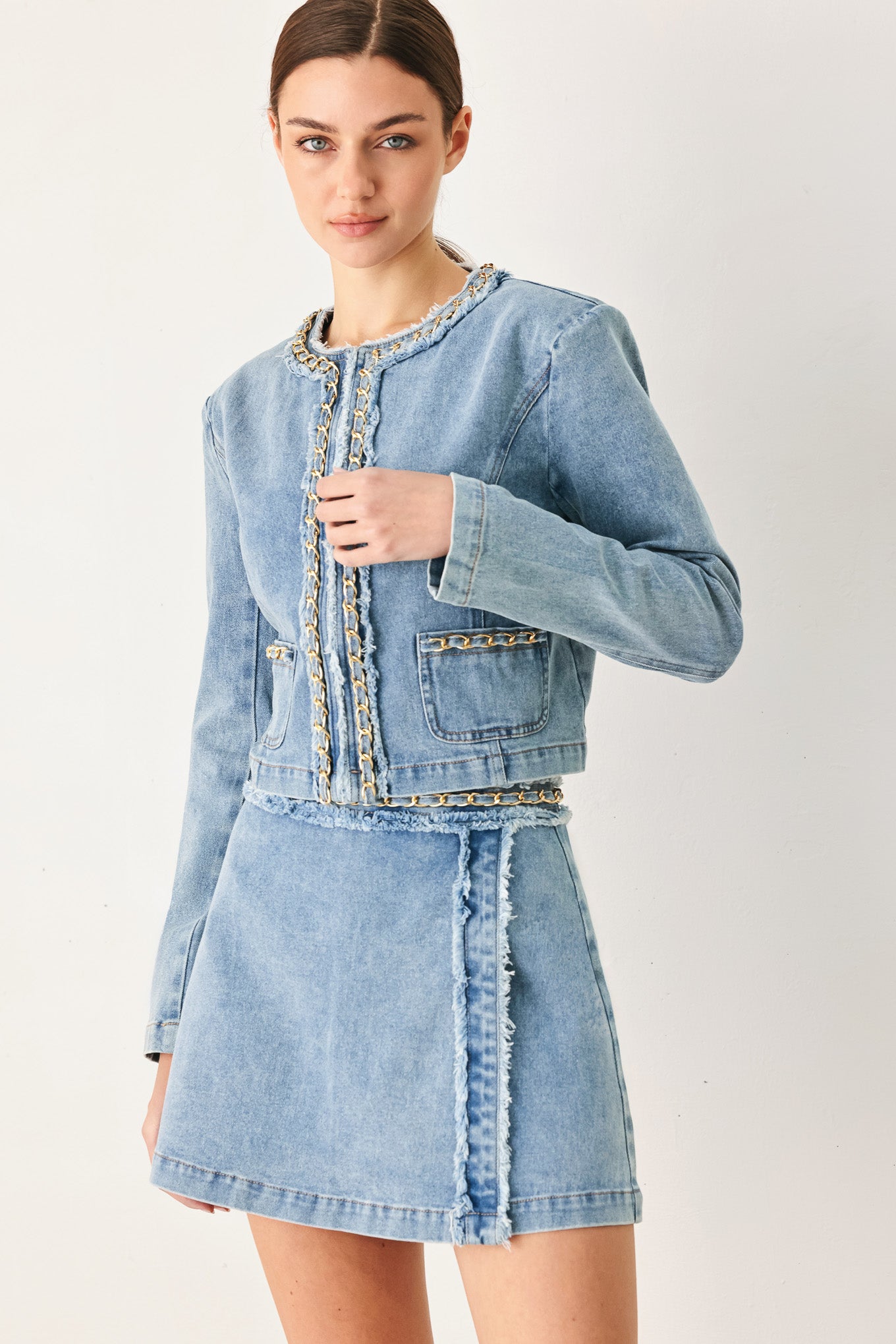 Woman wearing a light denim skort with fray edge, chain waist detail and back zipper closure | FREEMARKET