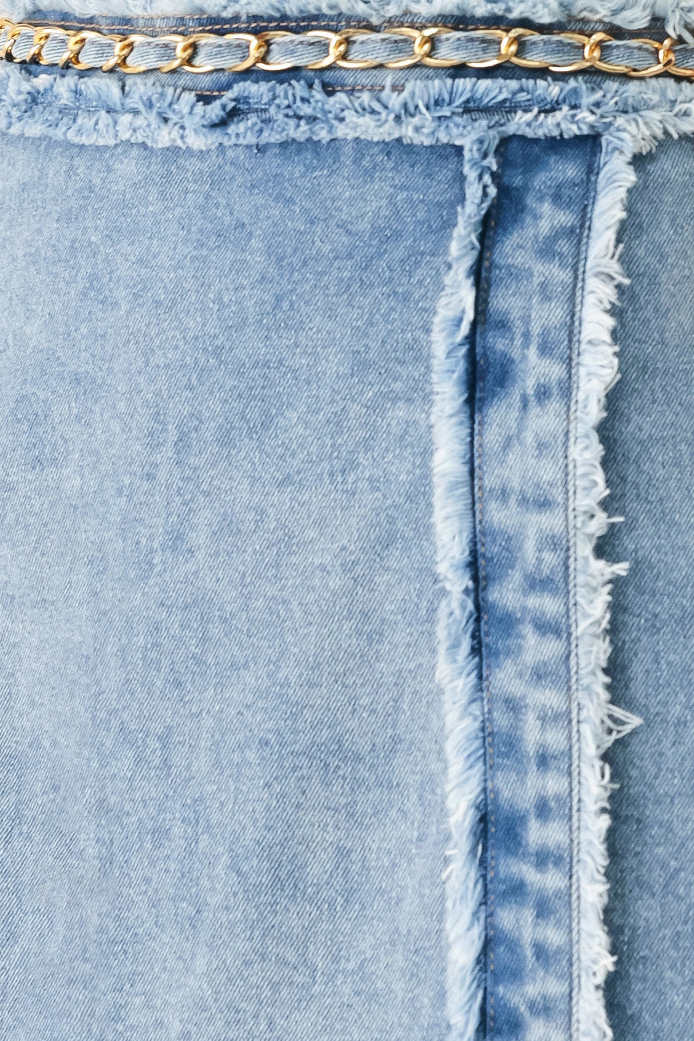 Woman wearing a light denim skort with fray edge, chain waist detail and back zipper closure | FREEMARKET