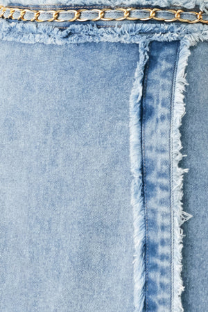 Woman wearing a light denim skort with fray edge, chain waist detail and back zipper closure | FREEMARKET