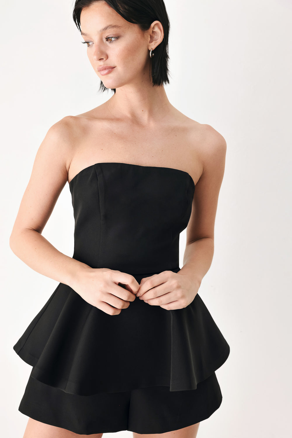 A woman modeling a black strapless peplum romper | FREEMARKET