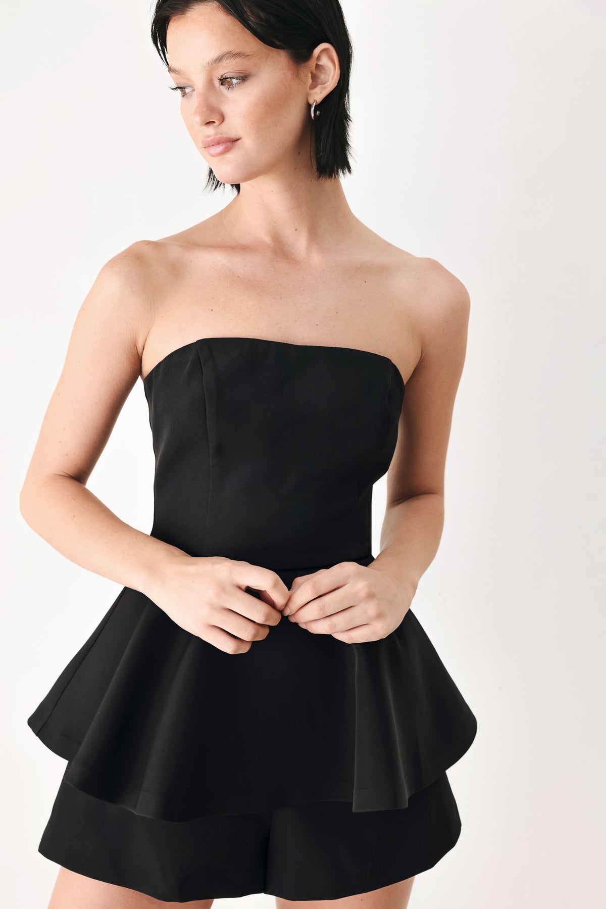 A woman modeling a black strapless peplum romper | FREEMARKET