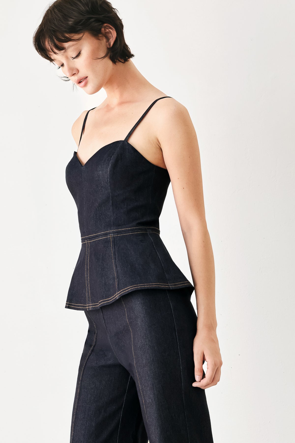 Woman wearing a dark denim jumpsuit with a peplum top and wide-leg pants style | FREEMARKET