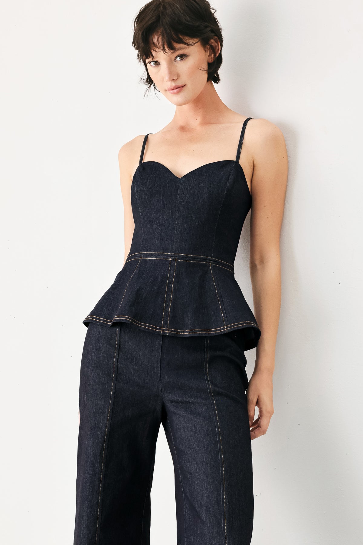 Woman wearing a dark denim jumpsuit with a peplum top and wide-leg pants style | FREEMARKET