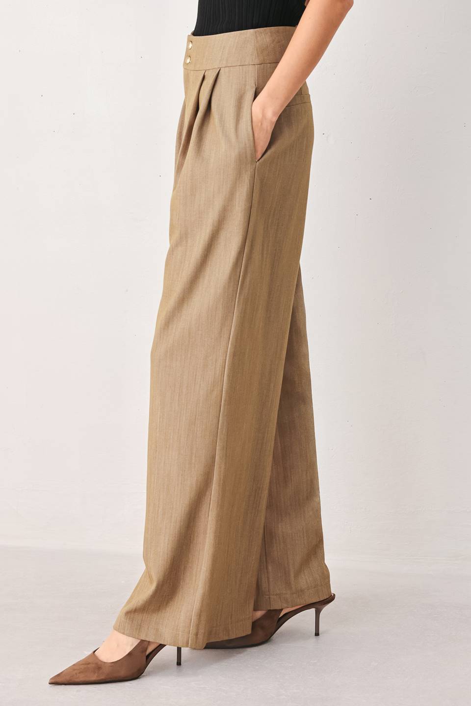 A model wearing high-waisted, wide-leg trousers in a light tan color with buttons | FREEMARKET