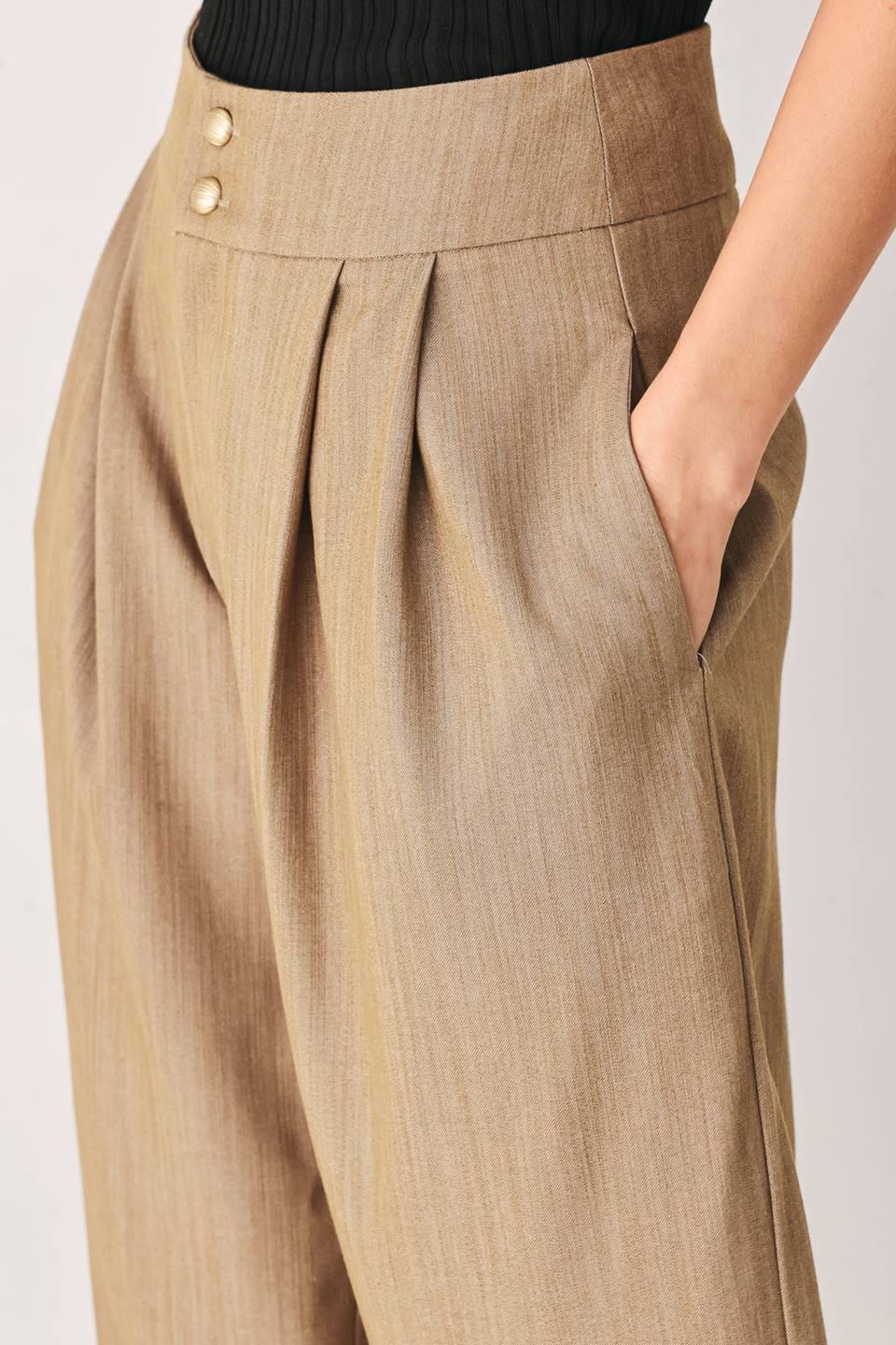 A model wearing high-waisted, wide-leg trousers in a light tan color with buttons | FREEMARKET