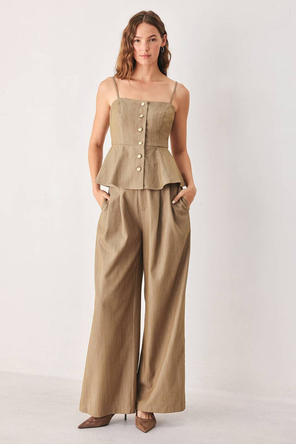 A model wearing high-waisted, wide-leg trousers in a light tan color with buttons | FREEMARKET