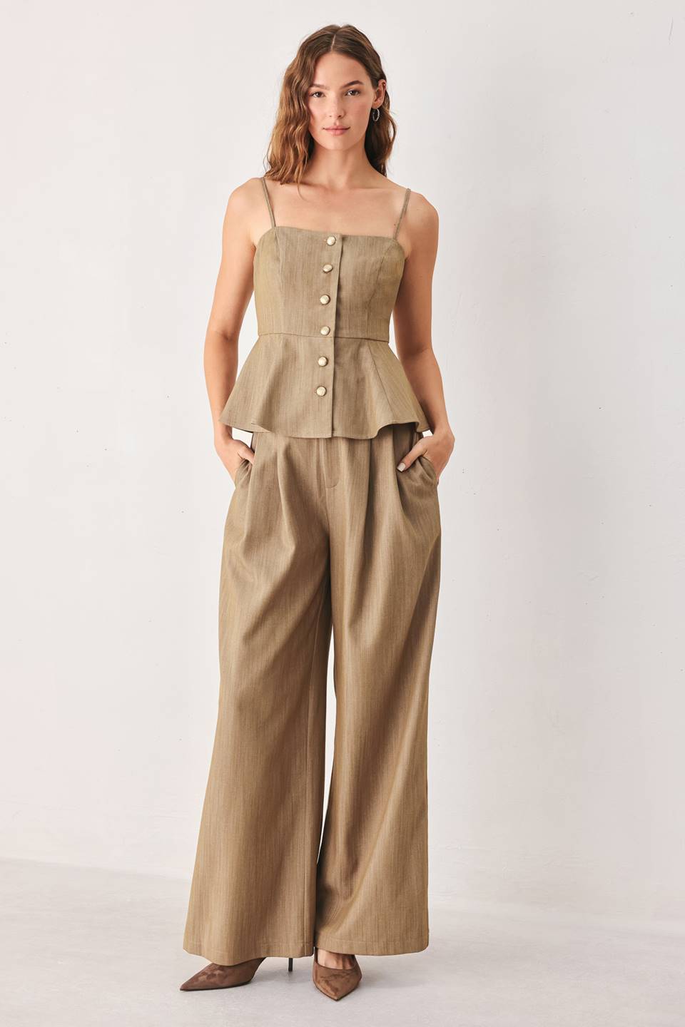 A model wearing high-waisted, wide-leg trousers in a light tan color with buttons | FREEMARKET