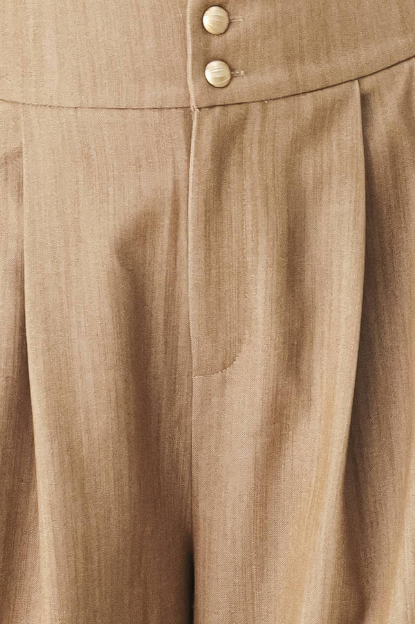 A model wearing high-waisted, wide-leg trousers in a light tan color with buttons | FREEMARKET