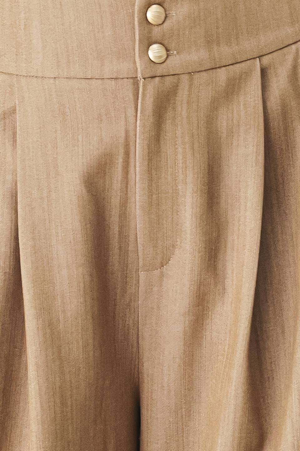 A model wearing high-waisted, wide-leg trousers in a light tan color with buttons | FREEMARKET