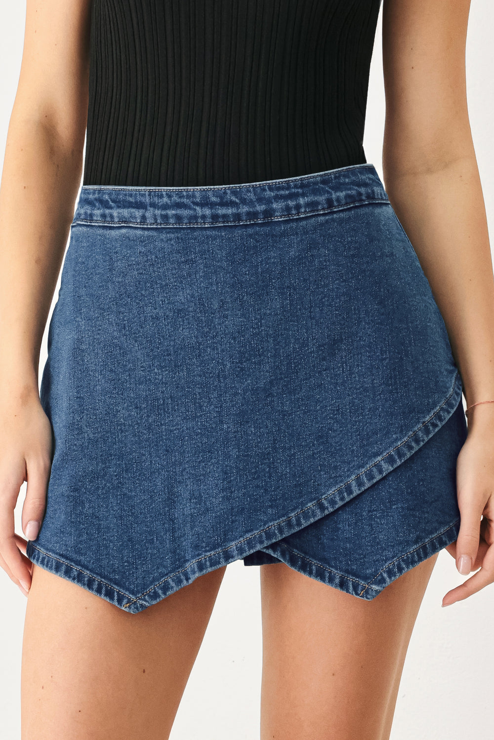 Woman wearing a blue denim mini skort with an asymmetrical wrap-style hem | FREEMARKET