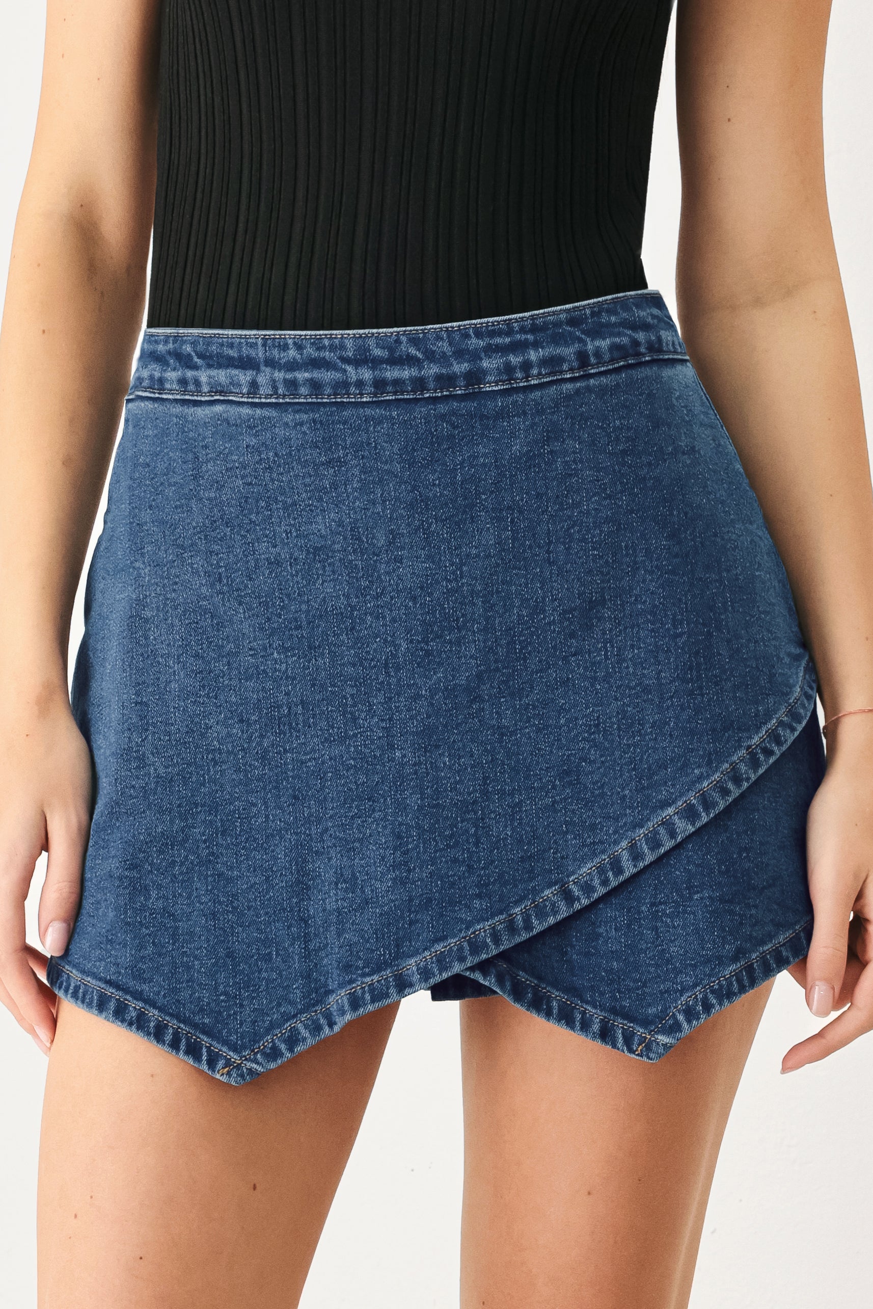 Woman wearing a blue denim mini skort with an asymmetrical wrap-style hem | FREEMARKET