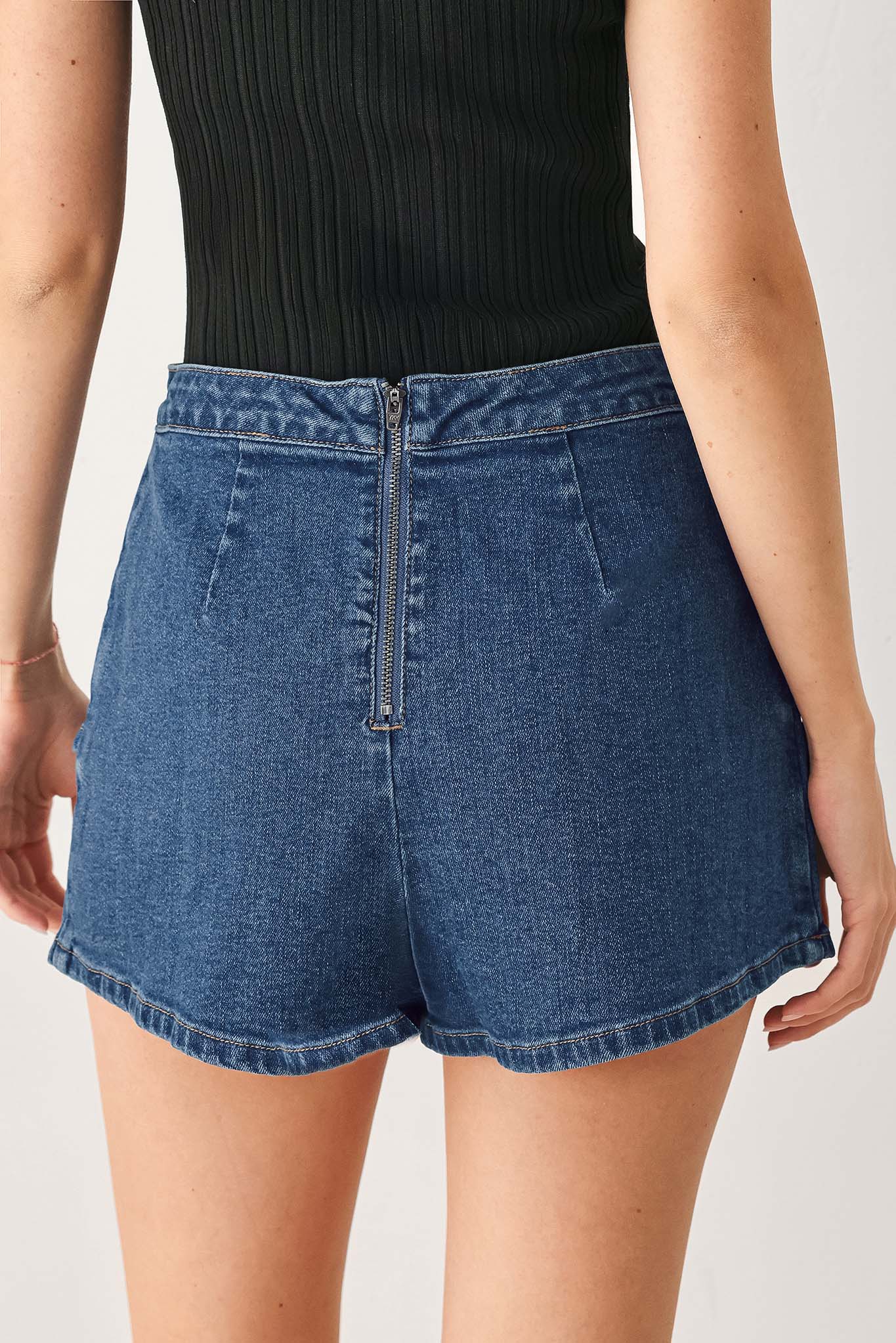 Woman wearing a blue denim mini skort with an asymmetrical wrap-style hem | FREEMARKET