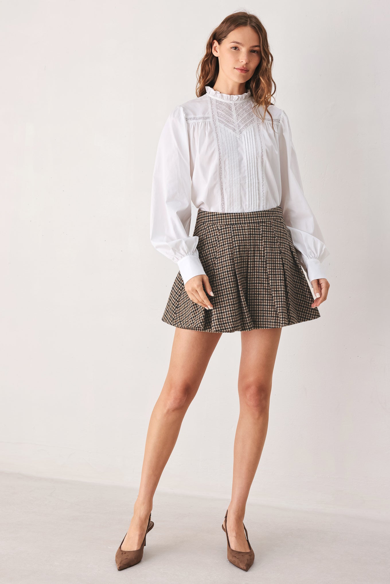 A close-up of a person wearing a brown and beige plaid pleated houndstooth mini skort | FREEMARKET