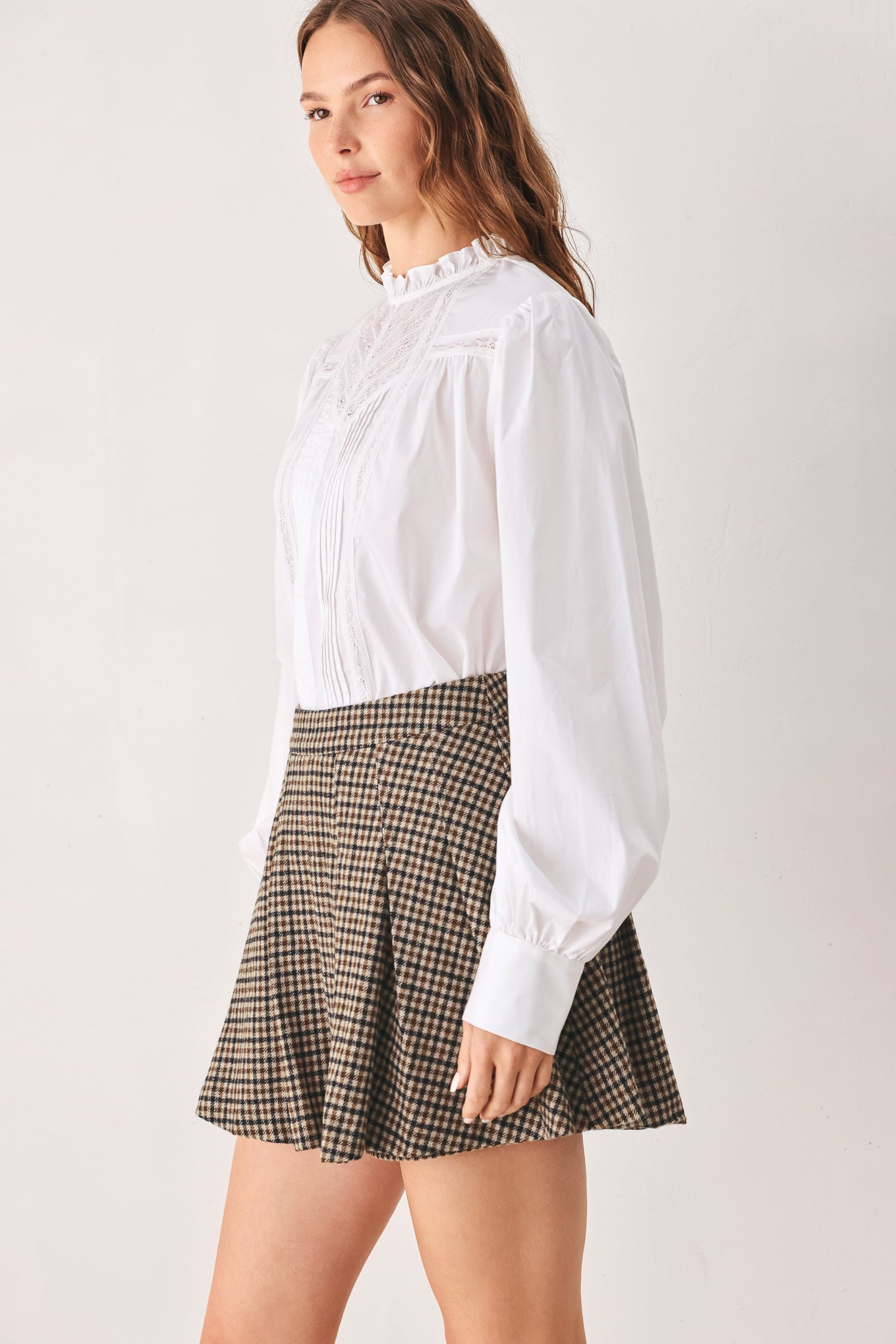 A close-up of a person wearing a brown and beige plaid pleated houndstooth mini skort | FREEMARKET