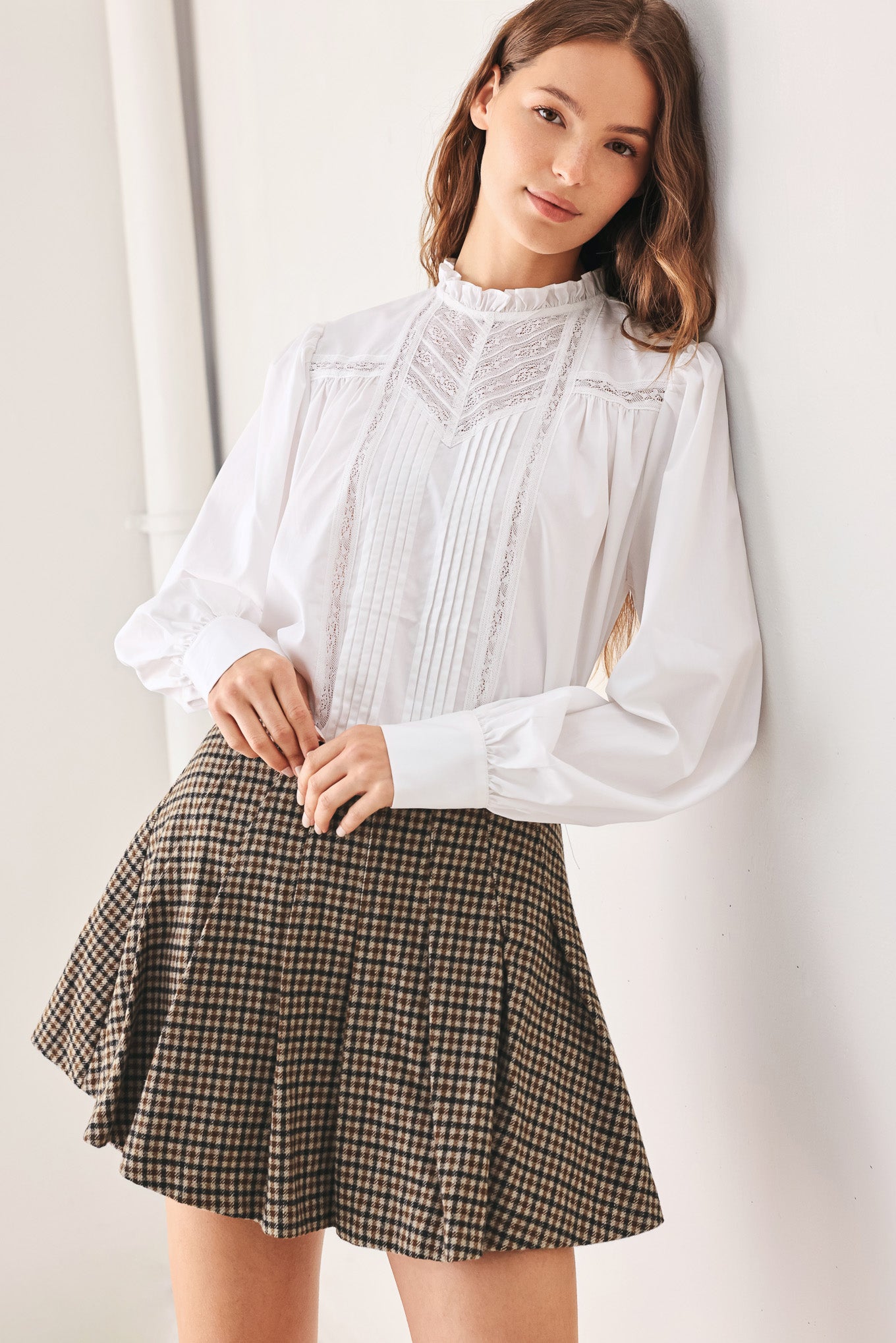 A close-up of a person wearing a brown and beige plaid pleated houndstooth mini skort | FREEMARKET