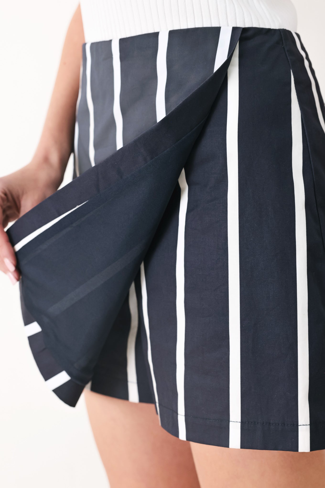 Woman wearing a navy blue and white striped skort with back zipper closure | FREEMARKET