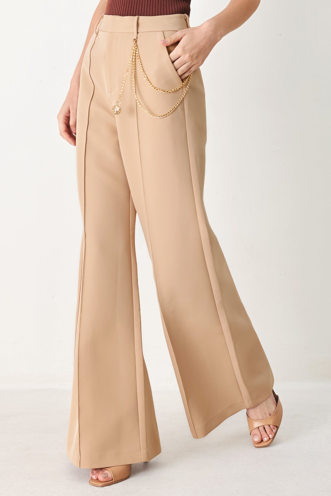 Woman wearing camel beige wide-leg pants with a chain detail on the side | FREEMARKET