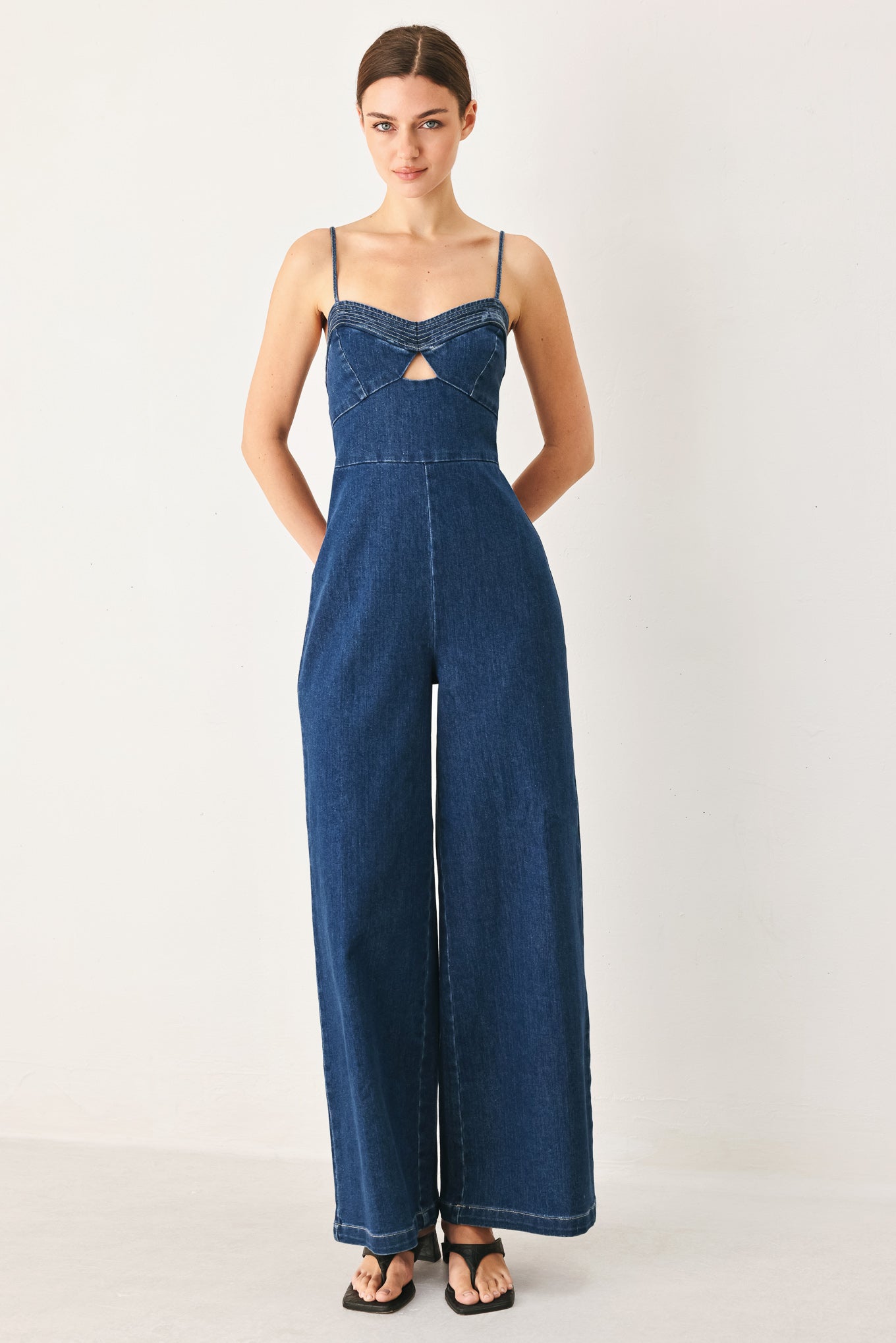 Woman wearing a blue denim jumpsuit on a white background
